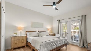 A bedroom with a bed, bedside lamps, a ceiling fan, and a window with curtains. - Modern Villa w/ Pool, Hot Tub & Theater Room! (Kissimmee)