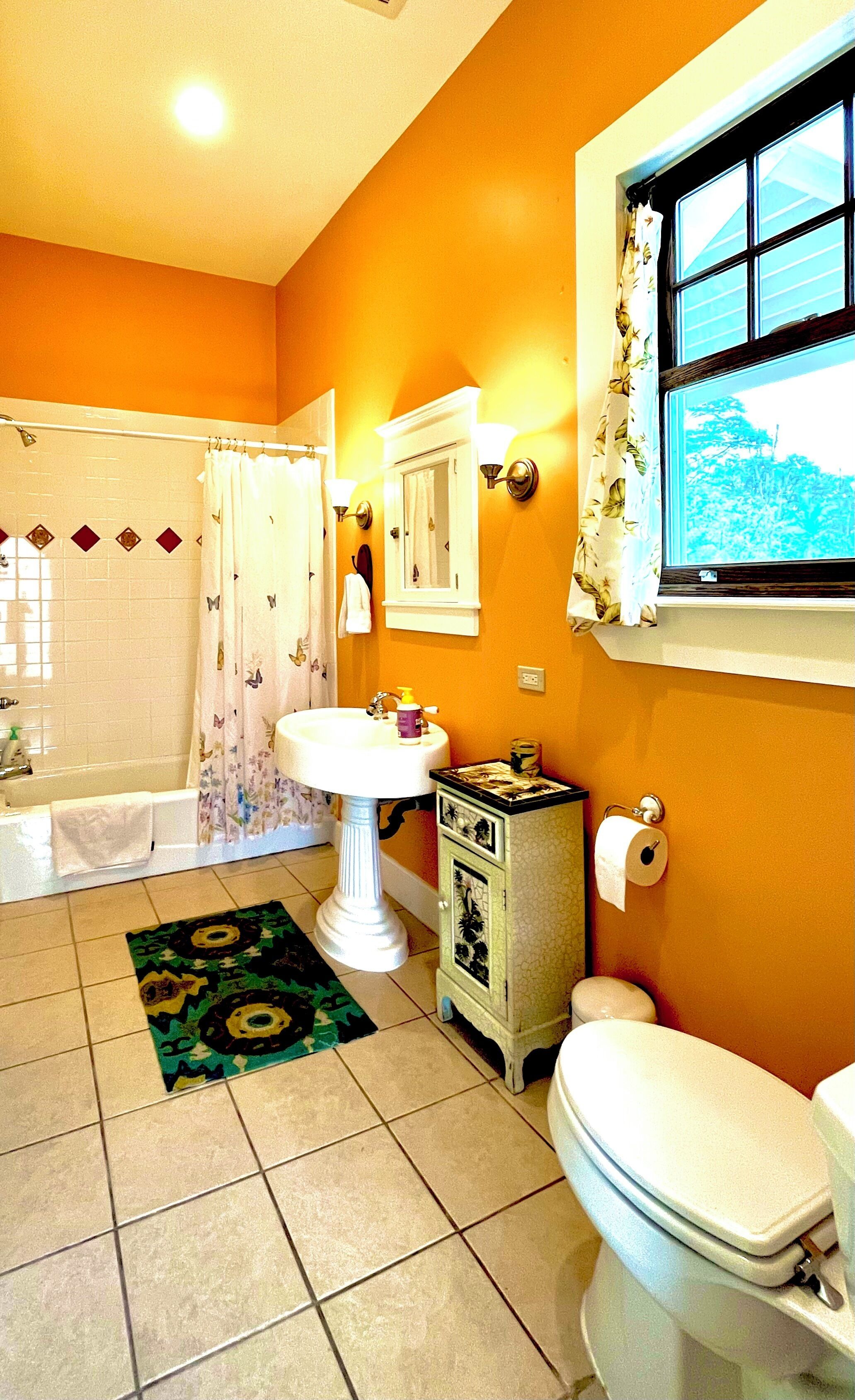 A bathroom with a bathtub, toilet, sink, and a window with a view of trees.