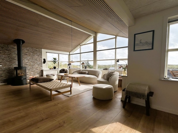 A spacious living room with a large window, a fireplace, and a cozy seating area.