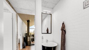 Un baño moderno con un lavamanos blanco, un inodoro negro y una toalla colgada en la pared.