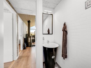 Een moderne badkamer met een witte wastafel, een zwart toilet en een handdoek aan de muur.