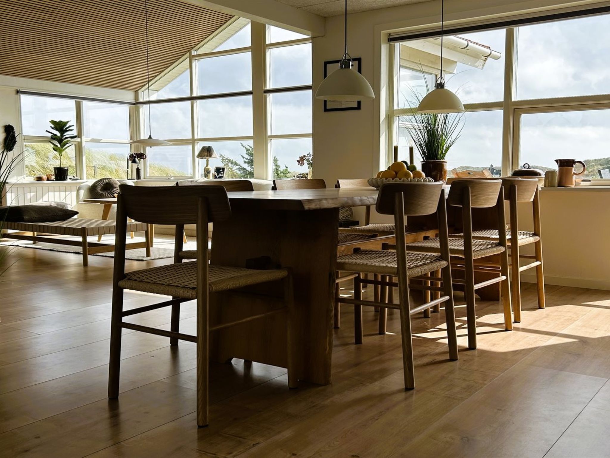 A spacious room with large windows, a wooden dining table, and chairs.