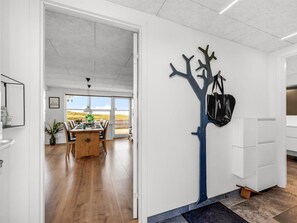 A modern kitchen with white cabinets, a blue tree-shaped wall art, and a view to the outdoors.