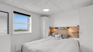 A bedroom with a large bed, a window with a view, a headboard with a sign, and a radiator.