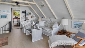 A cozy attic room with a high ceiling, a glass table, floral sofas, and a wooden chair. - "Luci" - 20m from the sea by Interhome (Martofte)