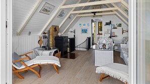 A cozy attic room with a high ceiling, a fireplace, a dining table, and a comfortable seating area. - "Luci" - 20m from the sea by Interhome (Martofte)