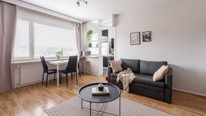Una sala de estar moderna con un sofá gris, una mesa de centro redonda y un comedor con una mesa y sillas blancas.