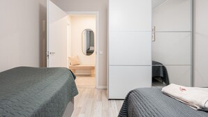 A bedroom with two beds, a wardrobe, and a bench. - Spacious Apartment with Prime Location (Jyväskylä)