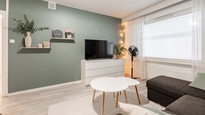 A living room with a TV, a white table, a sofa, and a fan. - Spacious Apartment with Prime Location (Jyväskylä)