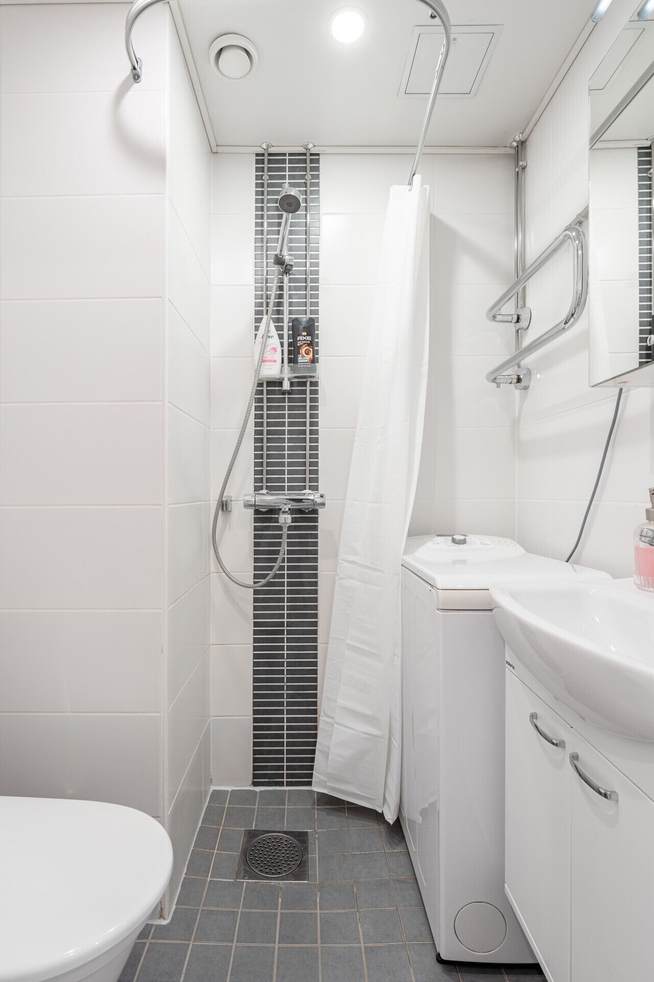 A modern bathroom with a shower, toilet, and sink.