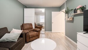 A modern living room with a brown leather sofa, a white coffee table, and a TV on a white stand. - Spacious Apartment with Prime Location (Jyväskylä)