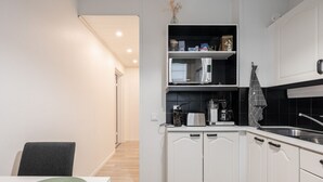 A modern kitchen with white cabinetry, a built-in microwave, and a coffee maker. - Spacious Apartment with Prime Location (Jyväskylä)