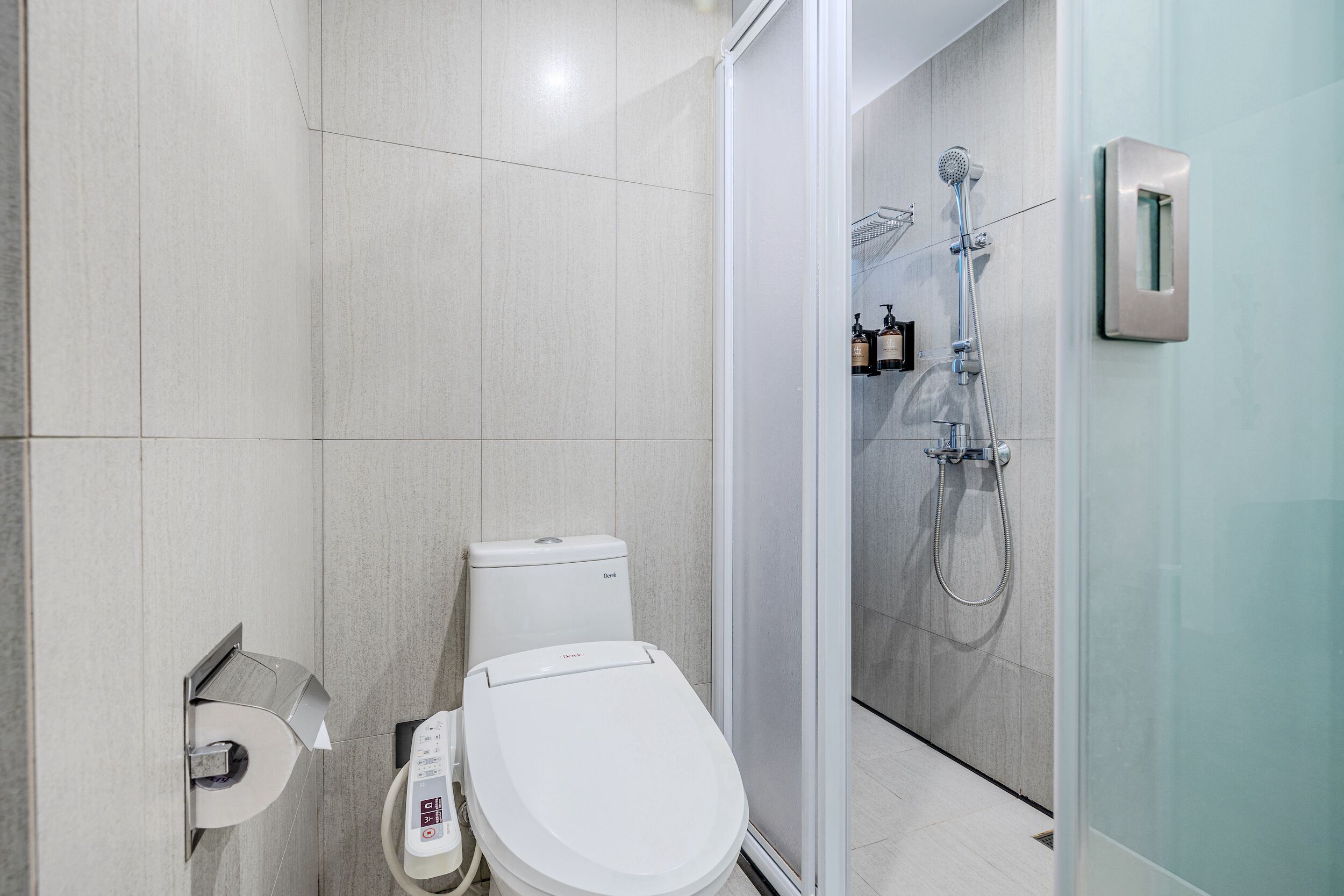 A modern bathroom with a toilet, a toilet paper holder, and a shower area with a glass door.
