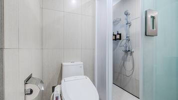 A modern bathroom with a toilet, a toilet paper holder, and a shower area with a glass door.