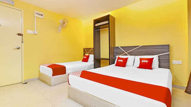A hotel room with two beds, each with red and white bedding, a mirror, and a wall-mounted fan. - De Mawardah Inn Hotel (Malacca City)