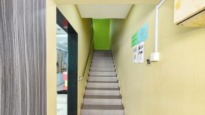A staircase in a building with a green wall at the top, a handrail, and informational posters on the walls. - De Mawardah Inn Hotel (Malacca City)