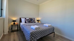 A bedroom with a bed, two bedside tables, a ceiling fan, and a window with curtains. - RedFlames Retreat@Gables/BoxHill/Marayla/RouseHill (Gables)