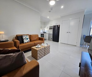 A modern living room with a sofa, a coffee table, and a dining area with a chair.