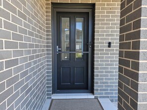 A black door with a metal handle, set in a brick wall with a small step leading up to it.