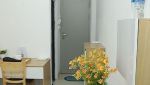 Ein kleiner, sauberer Raum mit Holztisch, Stuhl, Topfpflanze und Wasserspender.