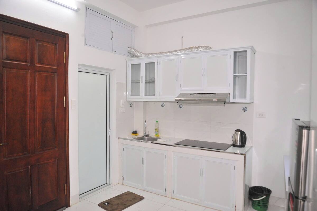 Une cuisine avec des armoires blanches, un réfrigérateur en acier inoxydable et une porte en bois.