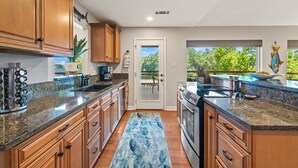A kitchen with wooden cabinets, granite countertops, a built-in oven, and a view through a glass door to an outdoor deck. - Lakefront Getaway w/Private Dock, Games and More (Hot Springs)