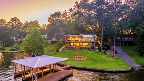 A lakeside property with a large house, a dock, and a well-maintained lawn. - Lakefront Getaway w/Private Dock, Games and More (Hot Springs)