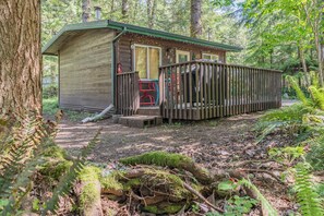 A wooden cabin with a porch, a small deck, and a door.