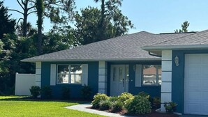 A single-story house with a front garage, a well-maintained lawn, and a small garden area with shrubs. - VacayTime/kingbdHotTub/nearbeach (Palm Coast)