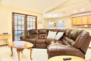 A living room with a brown leather sectional sofa, a wooden coffee table, and a small side table.