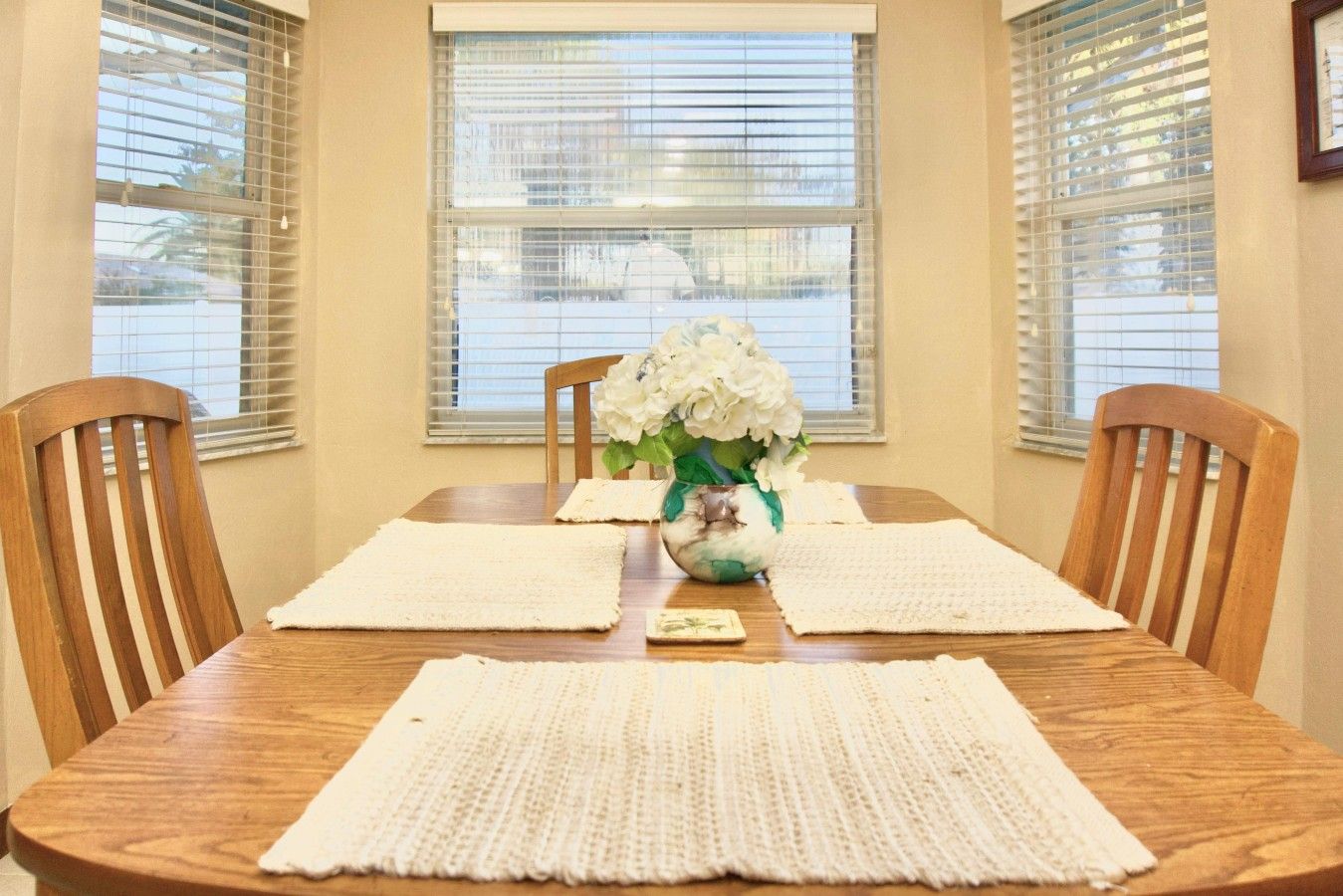 Een eettafel met een bloevas, twee placemats en een klein kaartje.