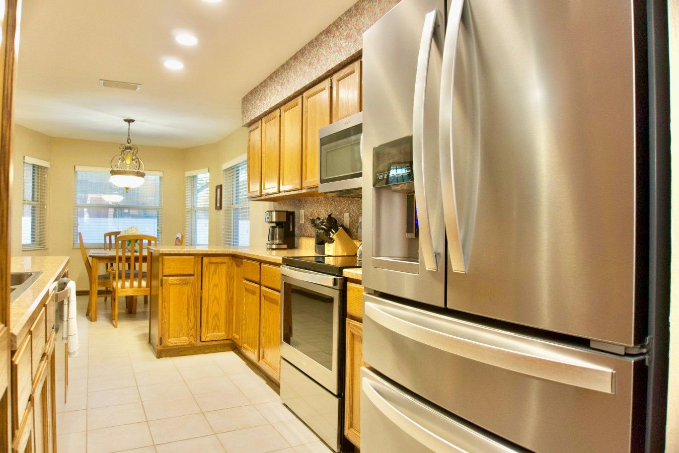 Una cocina moderna con electrodomésticos de acero inoxidable, armarios de madera y un comedor con una silla.