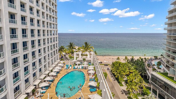 A hotel with a large pool, beach view, and multiple balconies. - Gorgeous Jr Suite on Pool and Lanai Level of Hotel (Fort Lauderdale)