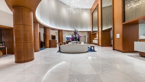 A spacious lobby with a central reception desk, large wooden columns, and a modern chandelier. - Gorgeous Jr Suite on Pool and Lanai Level of Hotel (Fort Lauderdale)