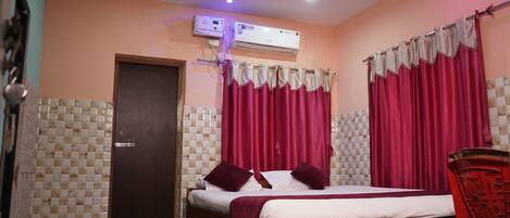A room with a bed, a door, an air conditioning unit, and curtains.