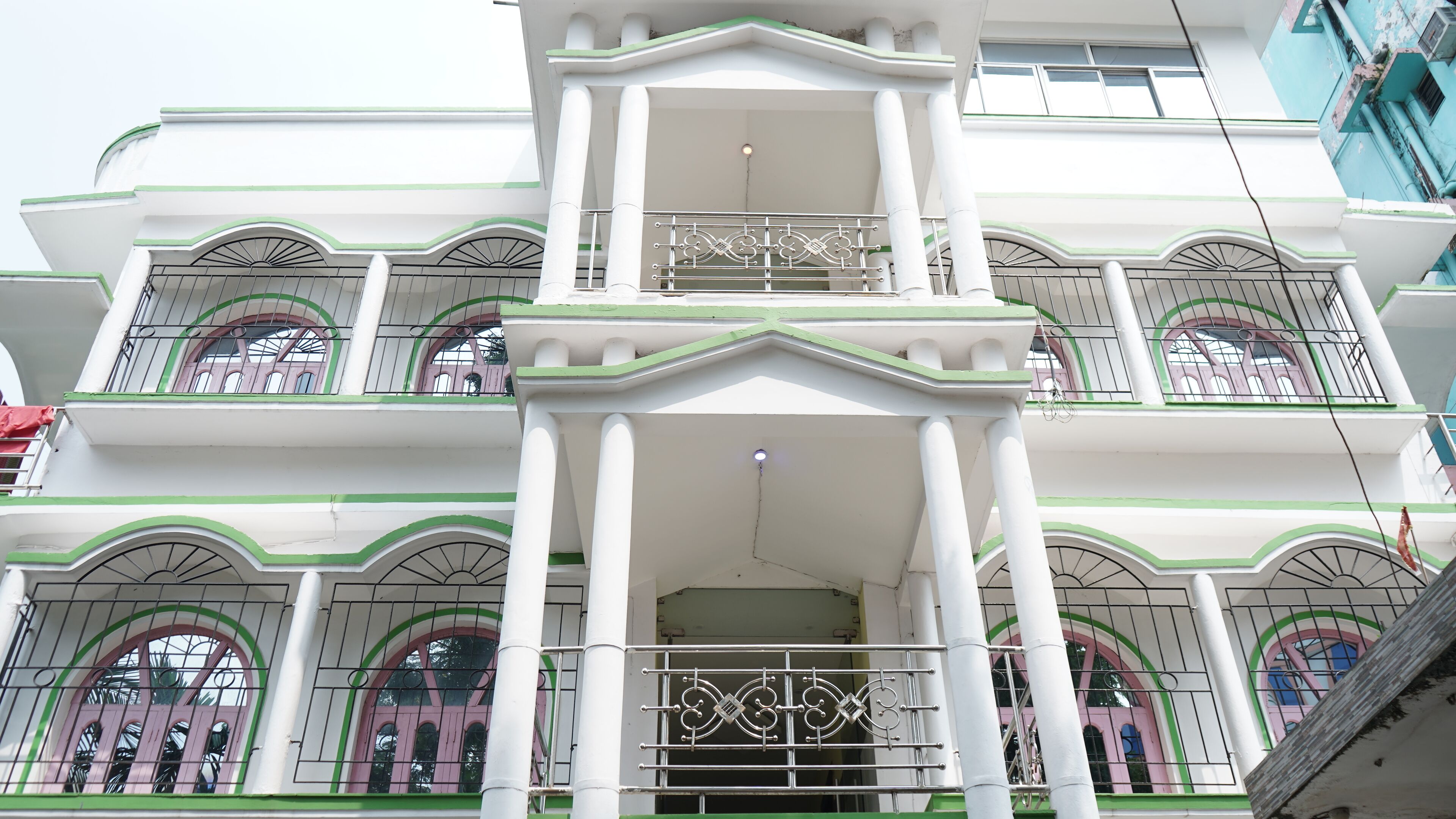 A multi-story building with balconies, large windows, and a central entrance with a metal gate.