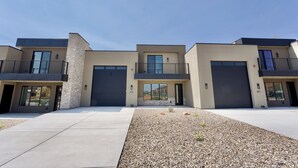 A modern multi-story residential building with a flat roof, large windows, and a central courtyard with gravel landscaping. - Red Rock Views & Stargazing near Zion & Bryce (Kanab)