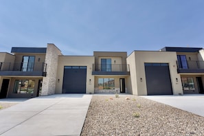 A modern multi-story residential building with a flat roof, large windows, and a central courtyard with gravel landscaping.