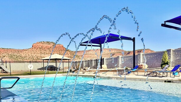 A pool with water jets, lounge chairs, and a view of red rock hills. - Red Rock Views & Stargazing near Zion & Bryce (Kanab)