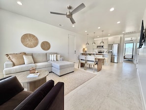 A modern living room with a sofa, coffee table, and dining area.