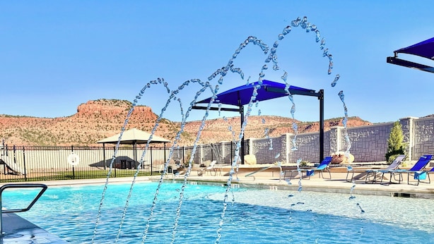 Una piscina con chorros de agua, sillones de descanso y vistas a colinas de roca roja.