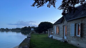 A stone building with a grassy yard and a body of water. - Waterfront house with large walled garden (Île-aux-Moines)