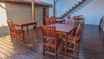 Una terraza de madera con mesas y sillas, un muro de ladrillo y una escalera.