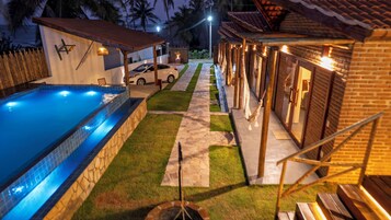 Una piscina con borde de piedra, un sendero pavimentado y una pequeña fuente.