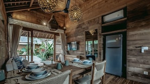 A wooden interior with a dining table set for four, surrounded by wicker chairs.