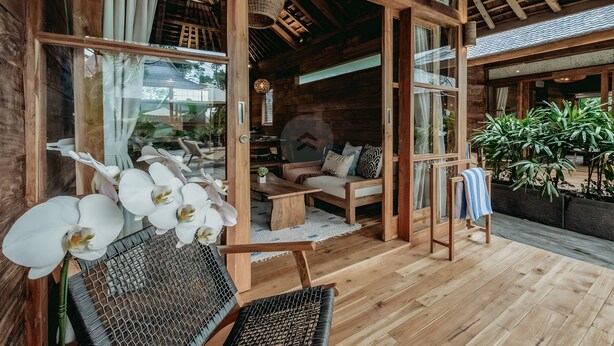 A wooden cabin interior with a sofa, chairs, and a dining table.