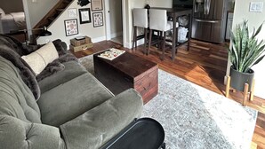 Sala de estar com sofá, mesa de centro e escada que leva a outro cômodo.