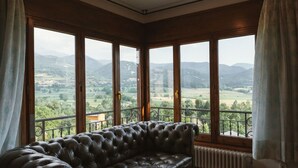 Habitación de esquina con sofá de cuero frente a amplios ventanales con vistas a un paisaje pintoresco.