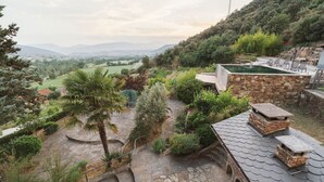 Un patio de piedra con vistas a un campo verde y montañas distantes.