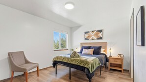 Une chambre à coucher avec un lit, une chaise, une table de chevet et une fenêtre.